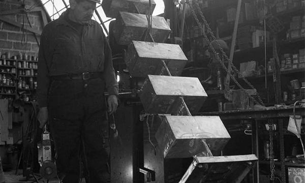 David Smith overseeing the placement of <em>Five Units Equal </em>(1956) onto a base in his workshop at Bolton Landing, 1956